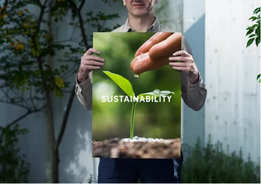 image of a man holding a poster board of a plant with the word sustainability listed in front of it