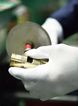 Photo close-up of factory worker using a sander device on a toto part.
