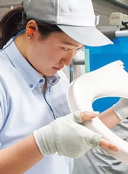 Photo of TOTO working inspecting a toilet seat for cracks or errors.