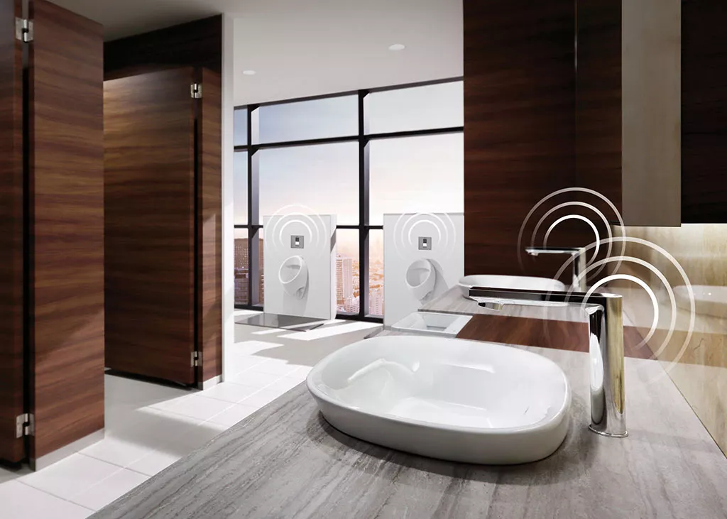 A modern commercial restroom features TOTO IoT-enabled fixtures, including TOUCHLESS smart faucets and connected flush valves.