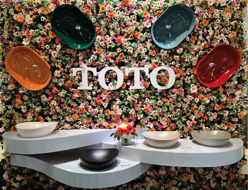 TOTO colorful vessel lavatories displayed on a floral wall at KBIS 2025, highlighting trending hues in bathroom design