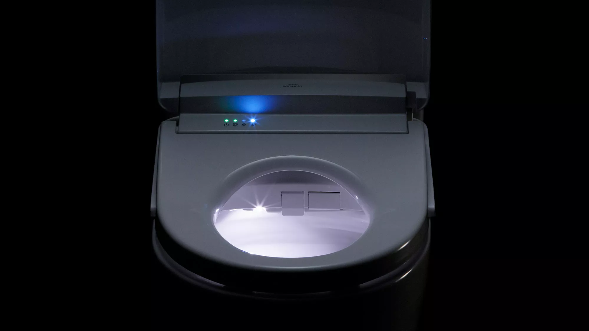 An S5 WASHLET bidet seat glows with soft LED lighting, illuminating the bowl and control indicators in a dark setting.