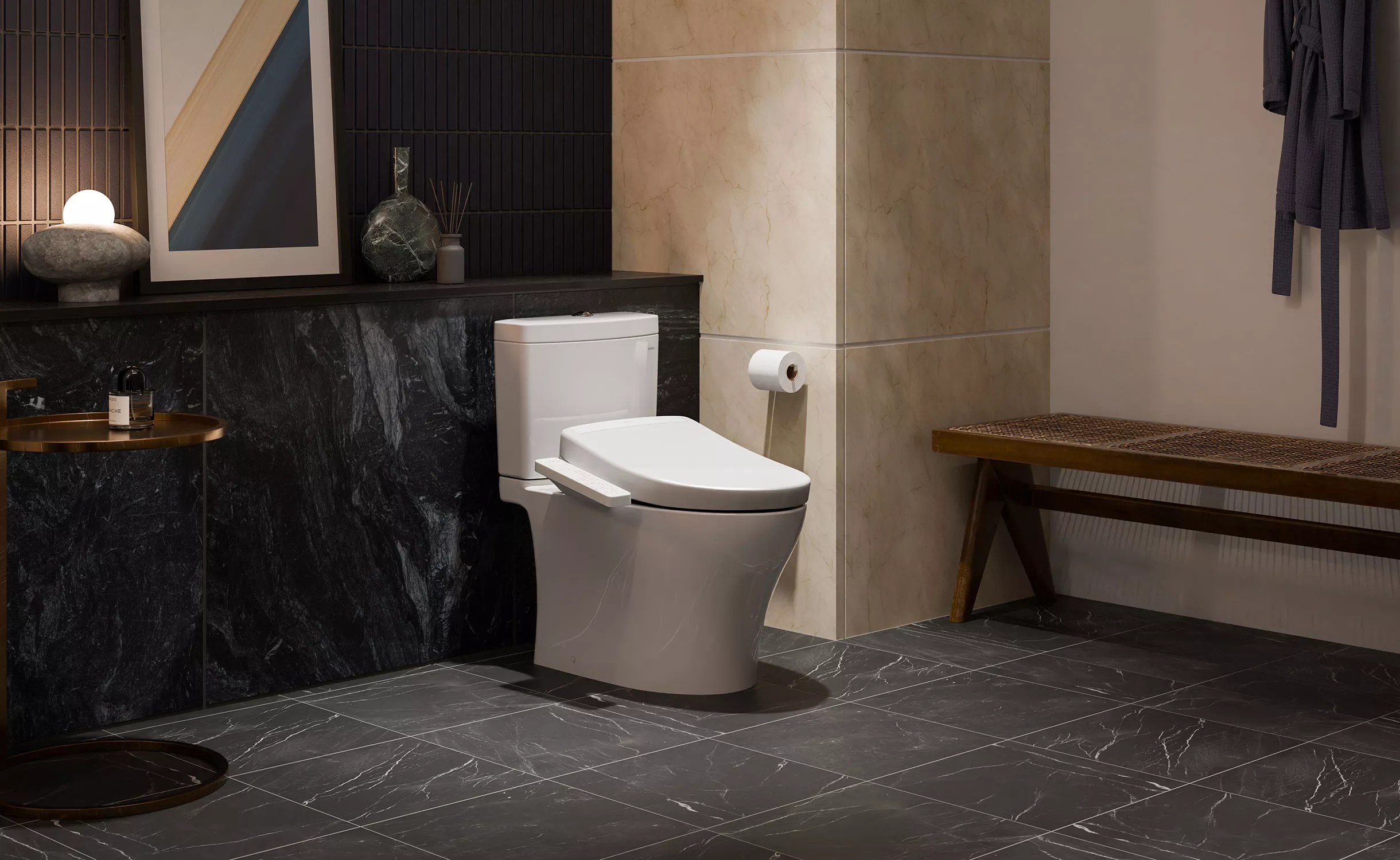 A modern bathroom featuring the TOTO Aquia IV toilet paired with a WASHLET S2 bidet seat. The space includes elegant dark marble tile flooring and wall accents, soft ambient lighting, and minimalist decor, creating a refined and spa-like atmosphere.