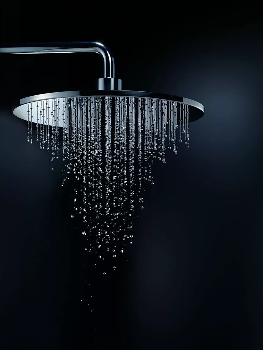 Chrome rainfall shower head with water droplets against a dark background, showcasing a luxurious and modern design