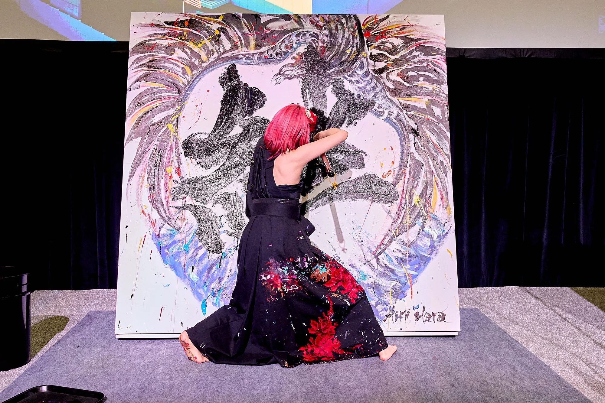 Japanese calligrapher Airi Hara performing live on stage, painting the kanji for “kizuna” during TOTO’s Morrow ribbon-cutting.