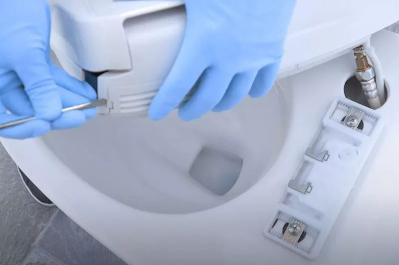 A professional TOTO factory-trained technician mounts a WASHLET bidet seat onto a toilet.